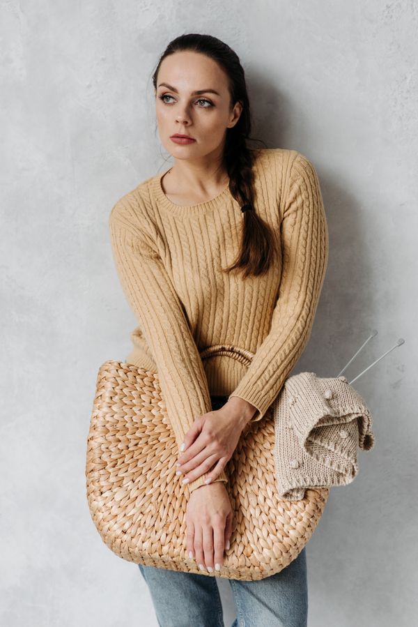 Frau in einem camelfarbenen Strickpullover